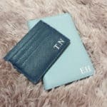 Mother's Day gifts - navy monogrammed card holder and a pastel blue silver foil stamped passport holder beautifully arranged on a mat